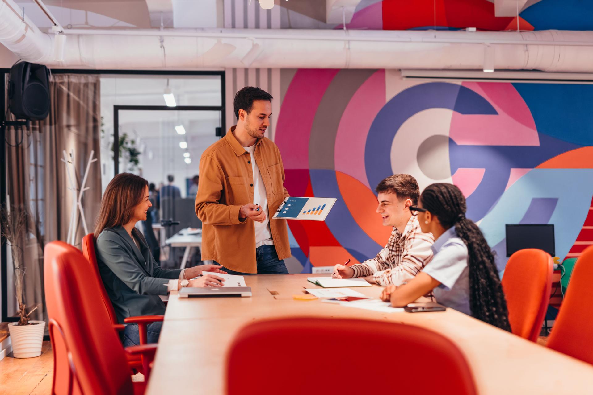 Young manager showing marketing results to his team in the office meeting